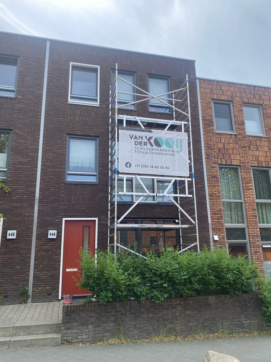 Woning in de steiger tijdens buitenschilderwerk aan kozijnen en gevel